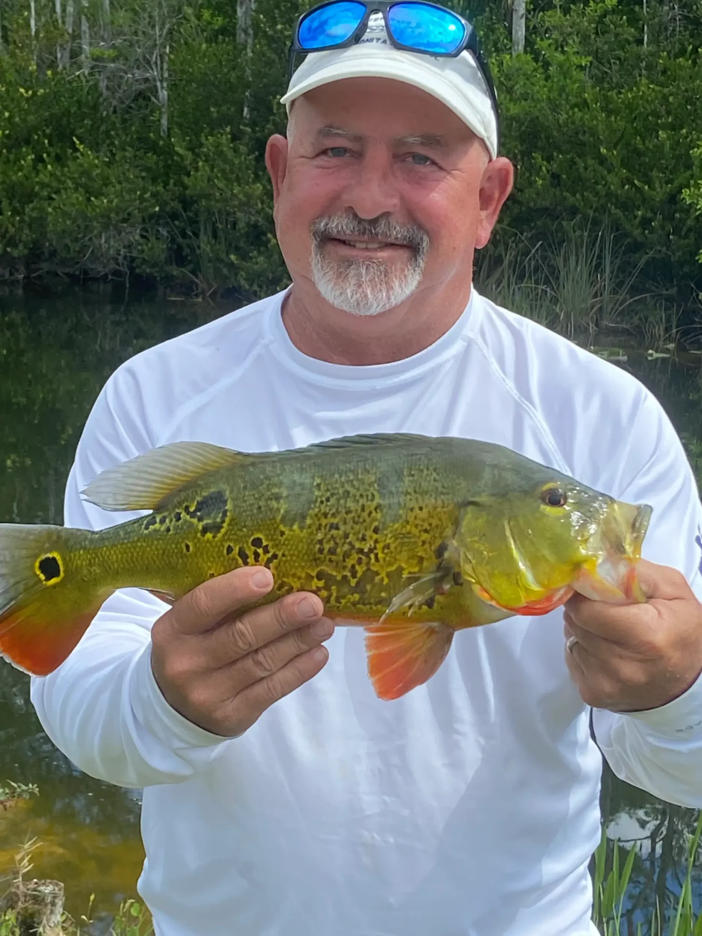 A man wearing a white sweater and holding a fish