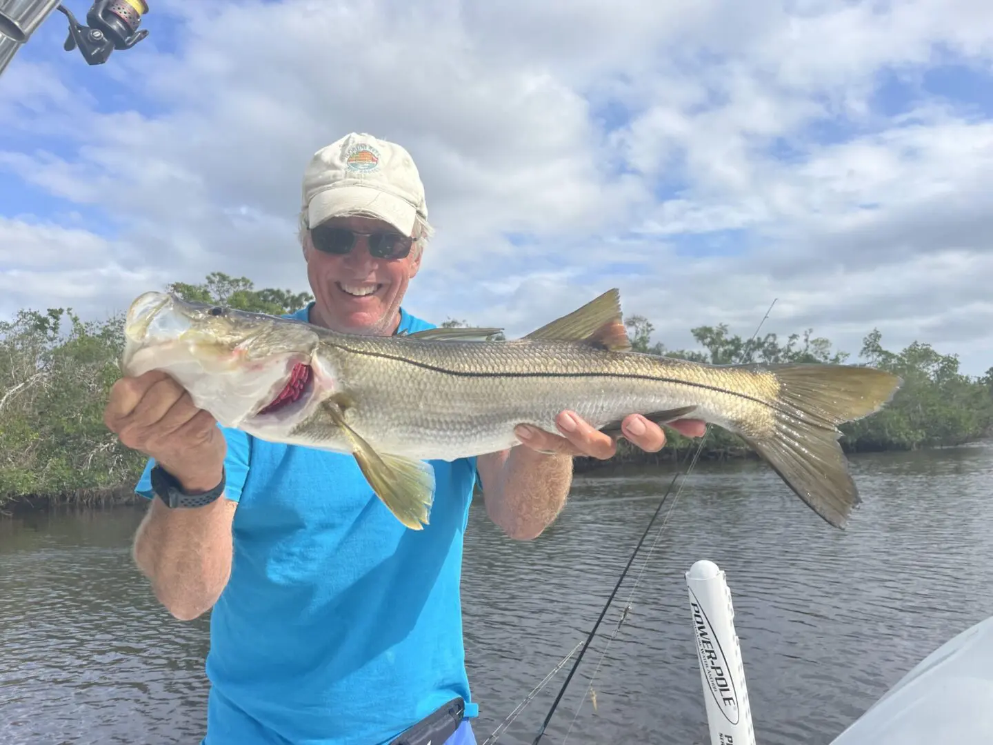 A senior man holding a fish on a boat