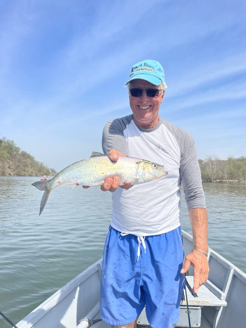 A man holding up a fish on a boat.