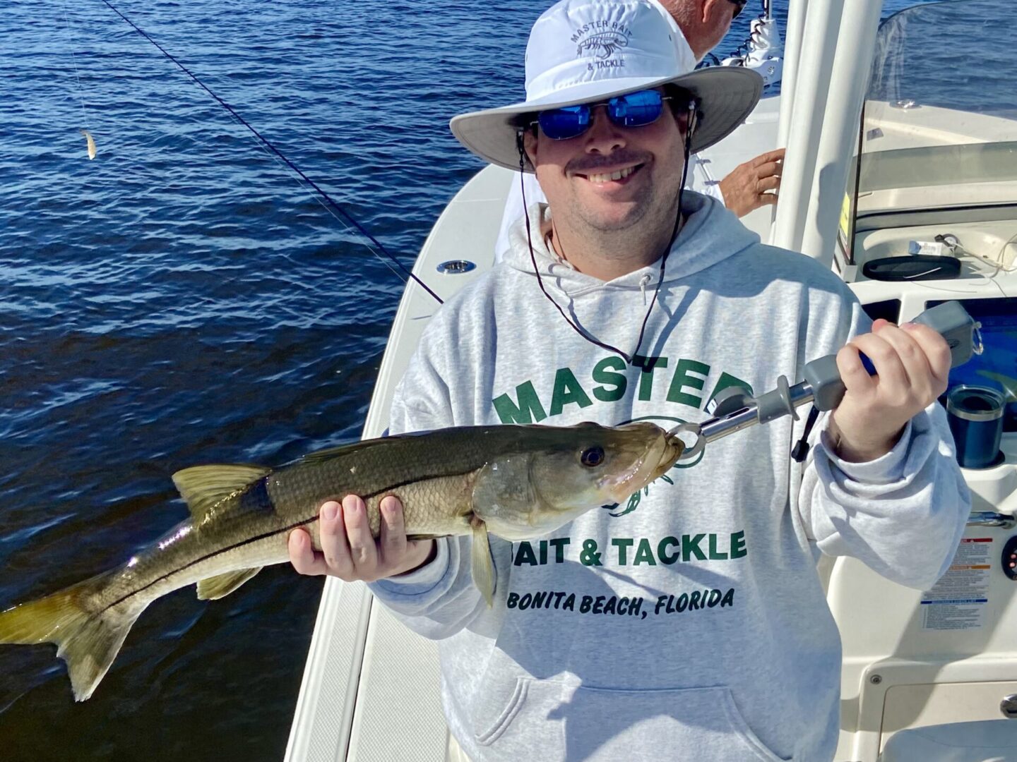 a man with hat holding a fish